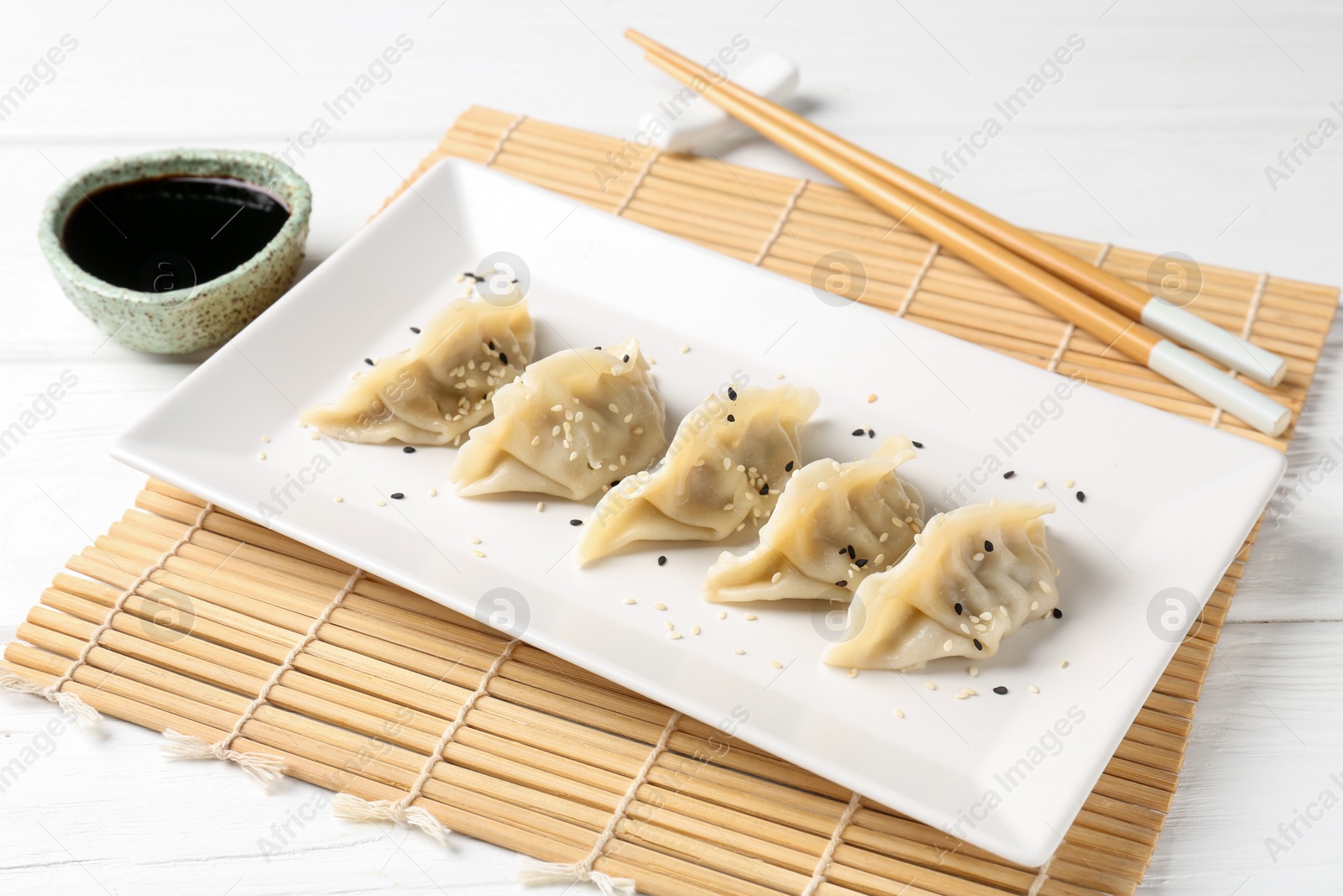 Photo of Delicious gyoza dumplings with sesame seeds served on white table