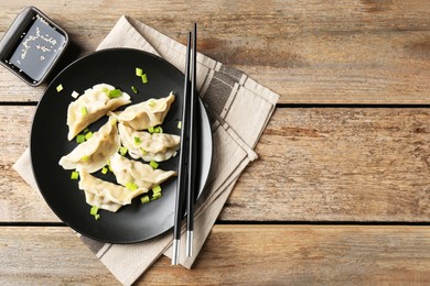 Photo of Delicious gyoza dumplings with chives served on wooden table, top view