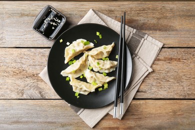 Photo of Delicious gyoza dumplings with chives served on wooden table, top view