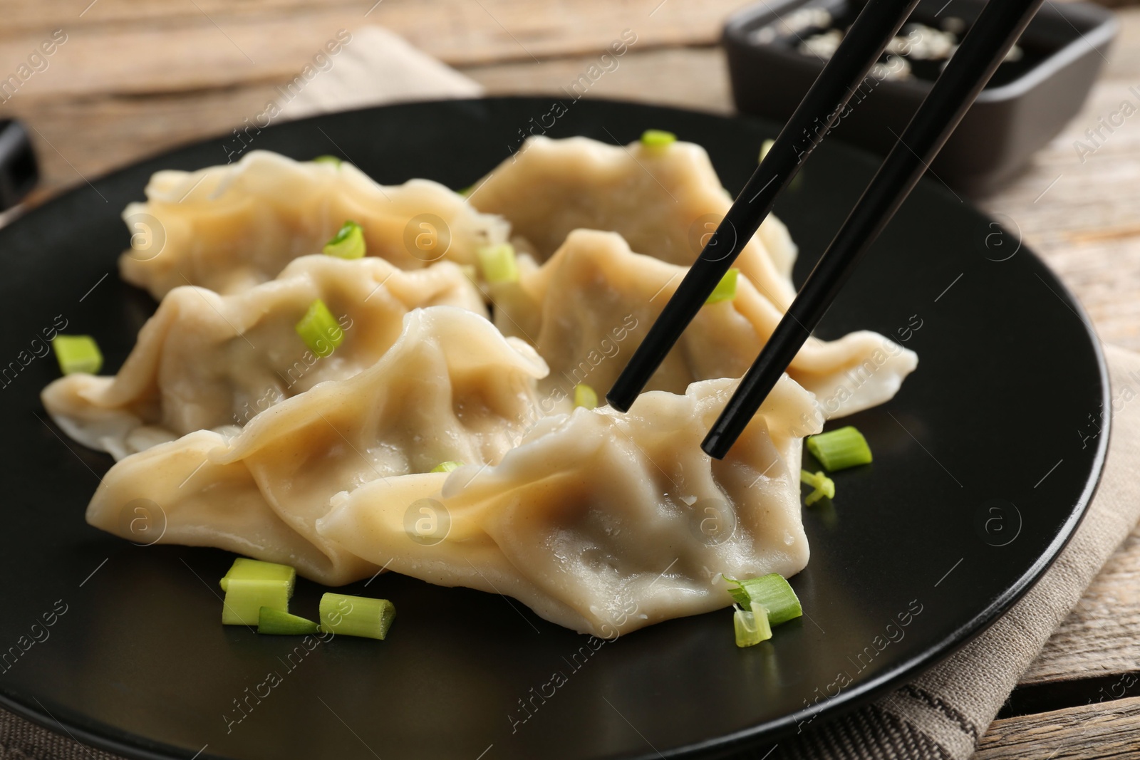 Photo of Eating tasty gyoza dumplings at wooden table, closeup