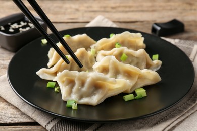 Photo of Eating tasty gyoza dumplings at wooden table, closeup