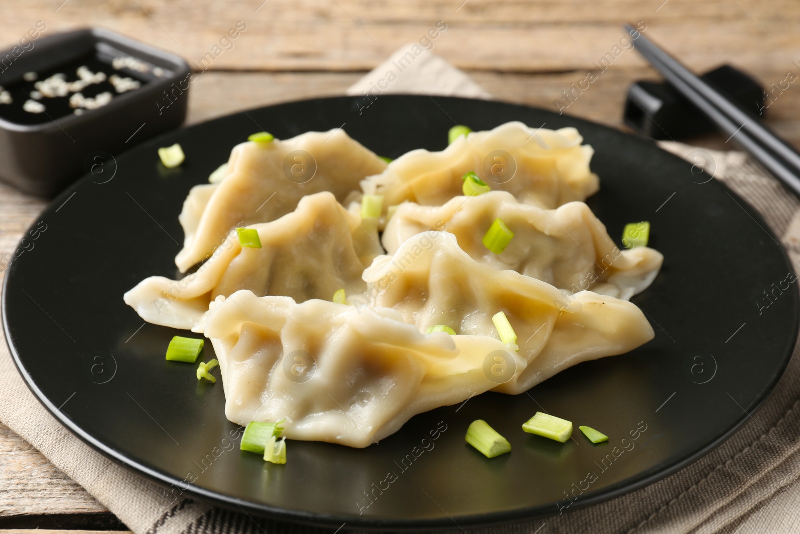 Photo of Delicious gyoza dumplings with chives served on wooden table, closeup