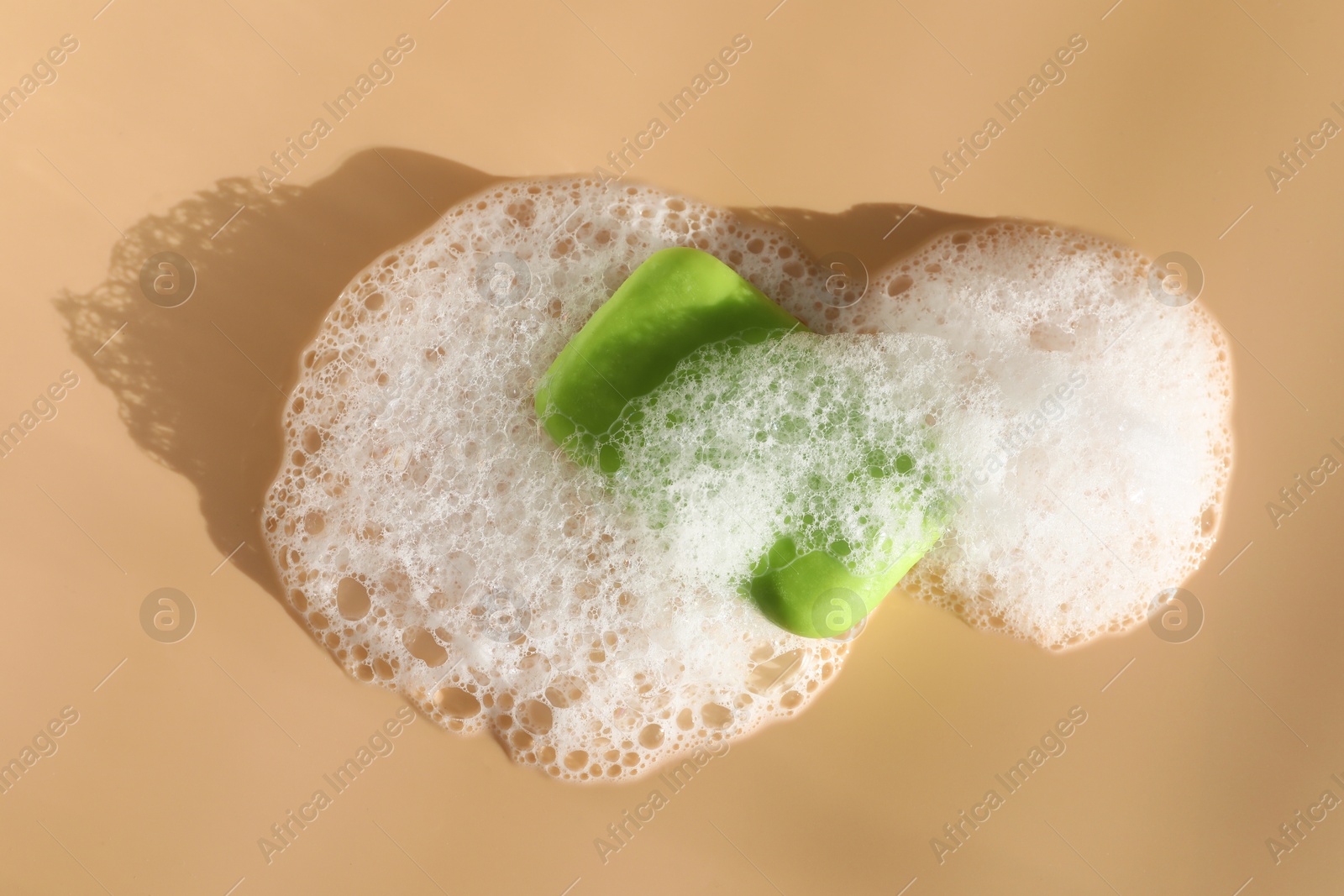 Soap bar with foam on peach background, top view Photo of Soap bar with foam on peach background, top view