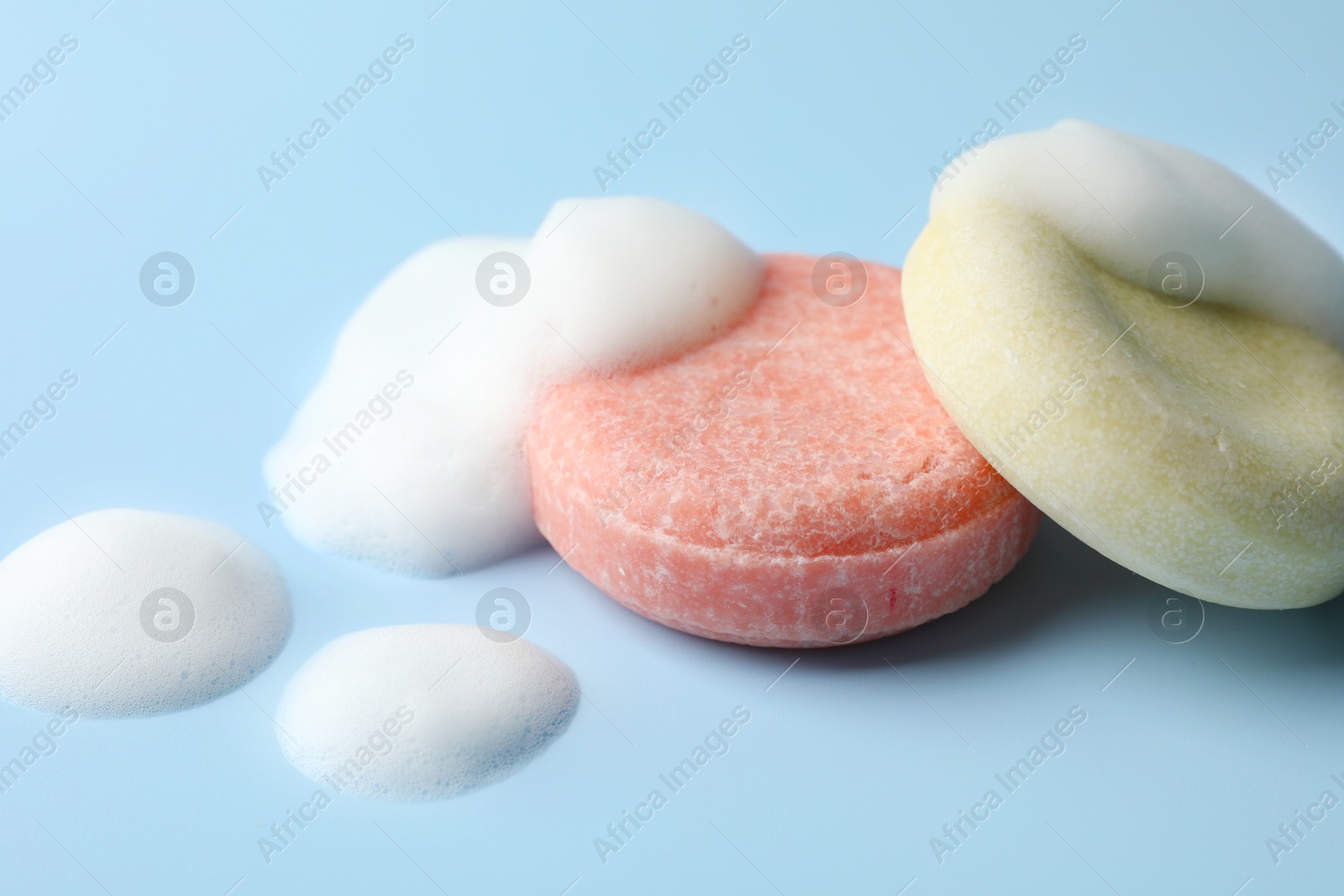 Soap bars with foam on light blue background, closeup Photo of Soap bars with foam on light blue background, closeup