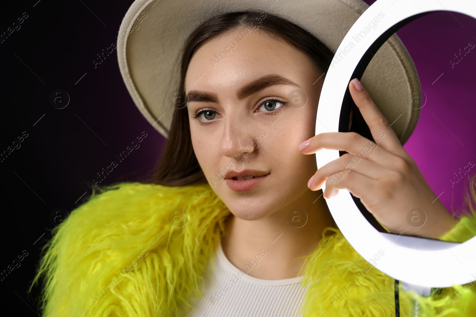 Photo of Stylish woman with ring lamp on dark purple background