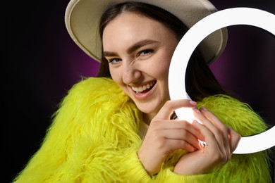 Photo of Stylish woman with ring lamp on dark purple background