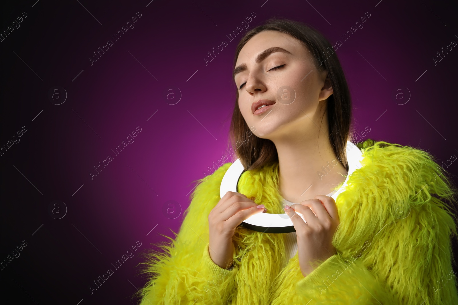 Photo of Stylish woman with ring lamp on dark purple background, space for text