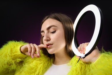 Photo of Stylish woman with ring lamp on dark purple background