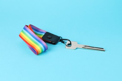 Photo of Key with keychain in LGBT colors on light blue background