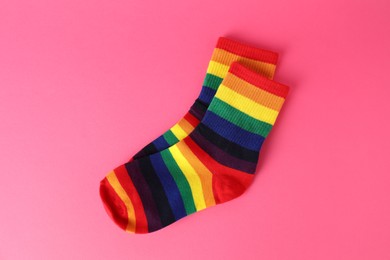 Photo of Pair of socks in LGBT colors on pink background, top view