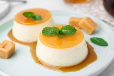 Photo of Tasty puddings with caramel sauce served on white table, closeup