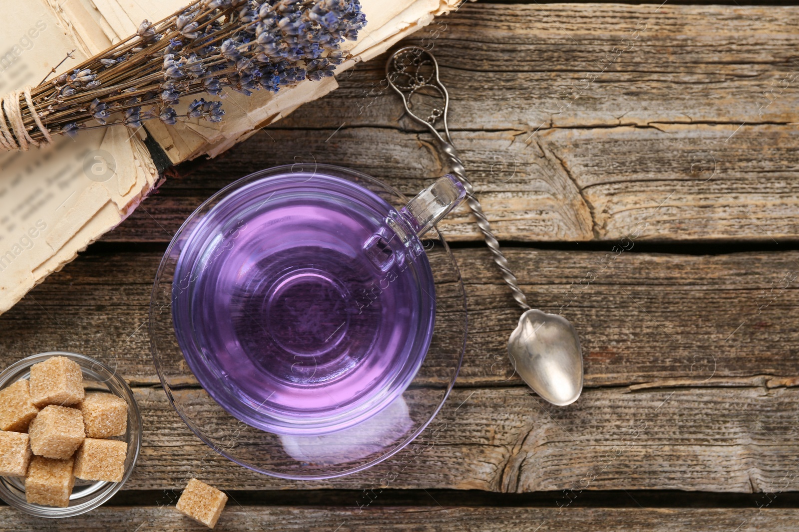 Aromatic lavender tea in cup, brown sugar, book, spoon and bunch of dry flowers on wooden table, flat lay. Space for text Photo of Aromatic lavender tea in cup, brown sugar, book, spoon and bunch of dry flowers on wooden table, flat lay. Space for text