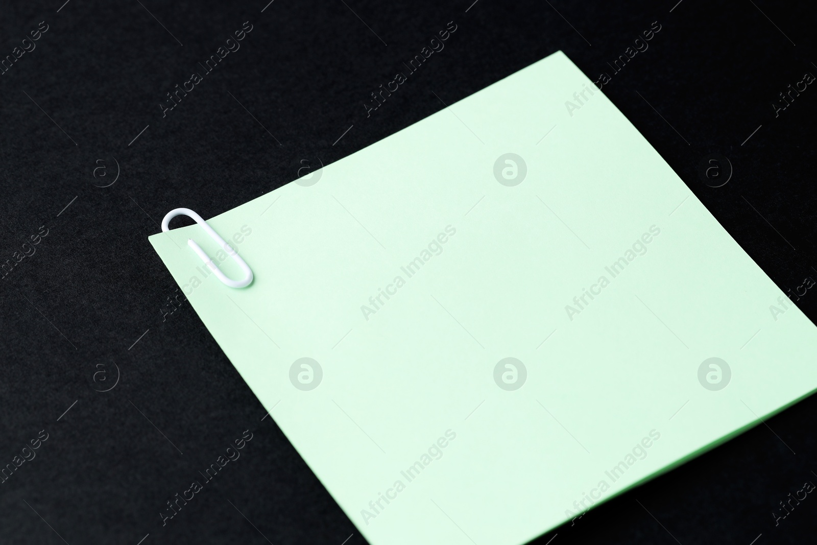 Photo of Paper notes with clip on black table, closeup. Space for text