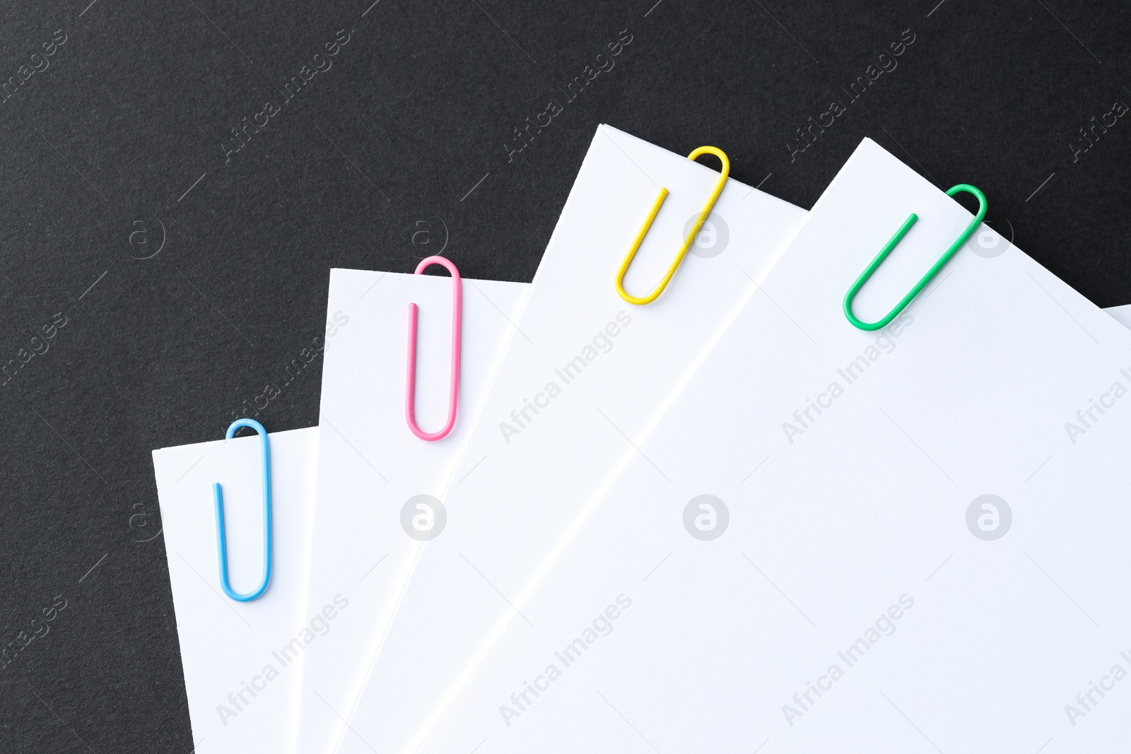 Photo of Paper notes with clips on black table, top view