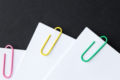 Paper notes with clips on black table, top view