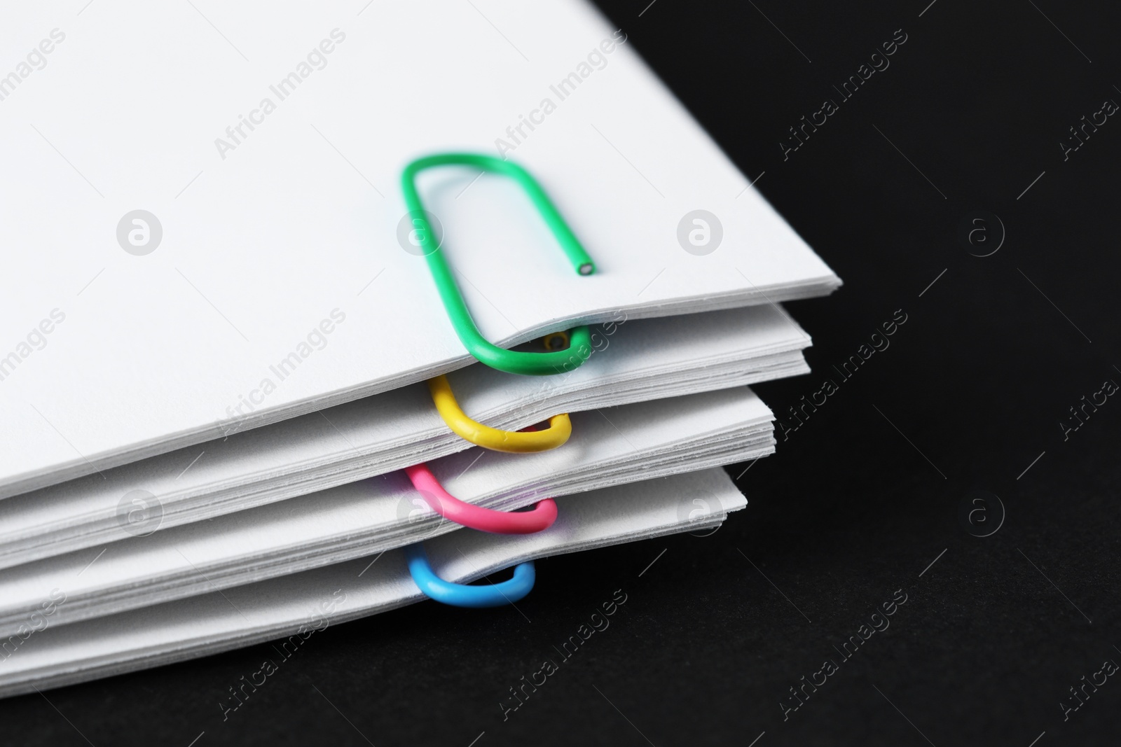 Photo of Paper notes with clips on black table, closeup