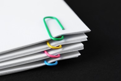 Paper notes with clips on black table, closeup