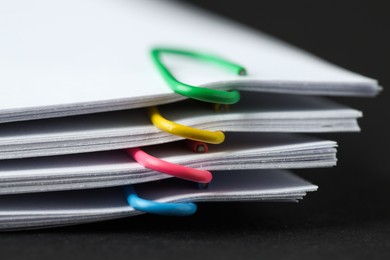 Paper notes with clips on black table, closeup