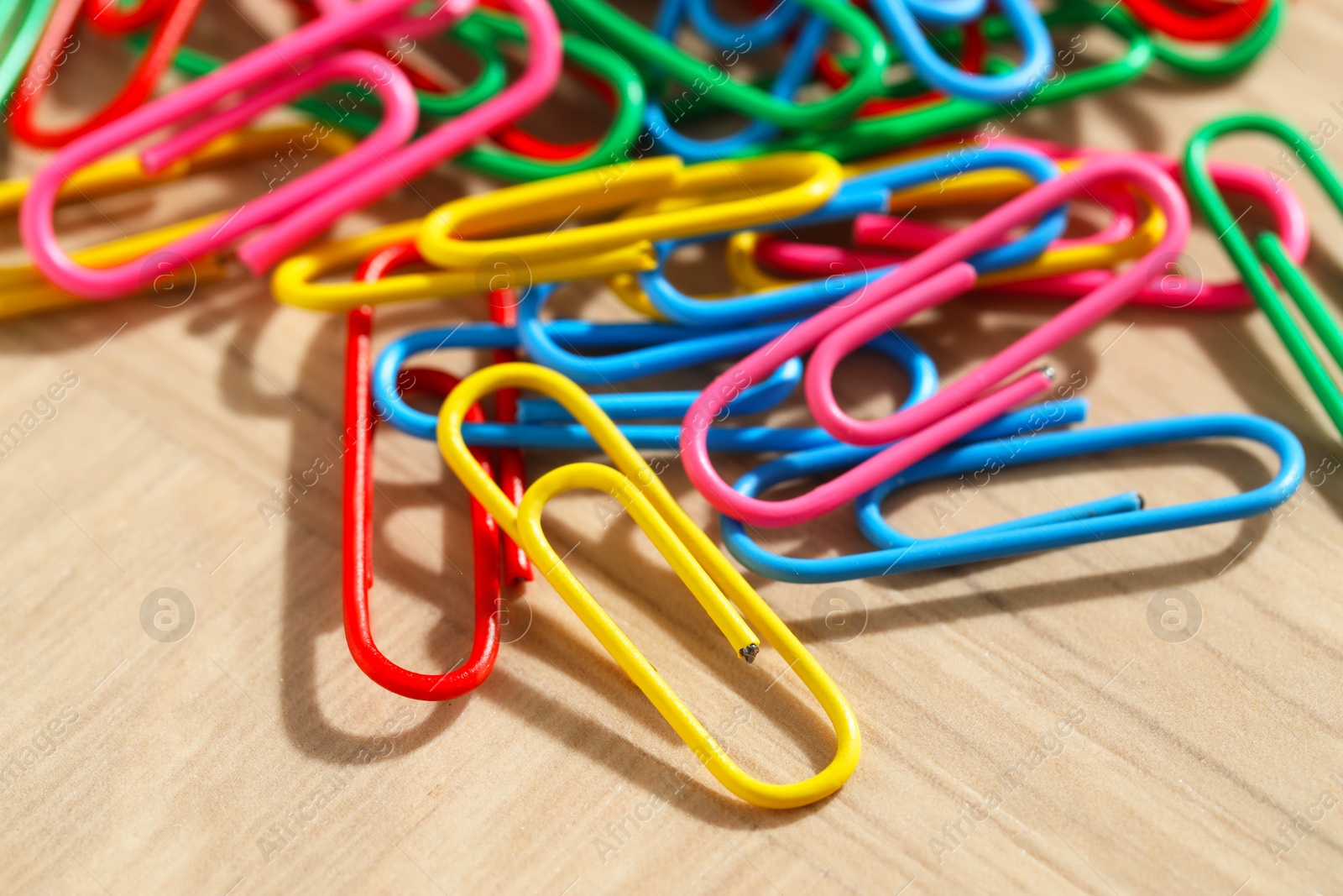 Photo of Many colorful paper clips on wooden table, closeup