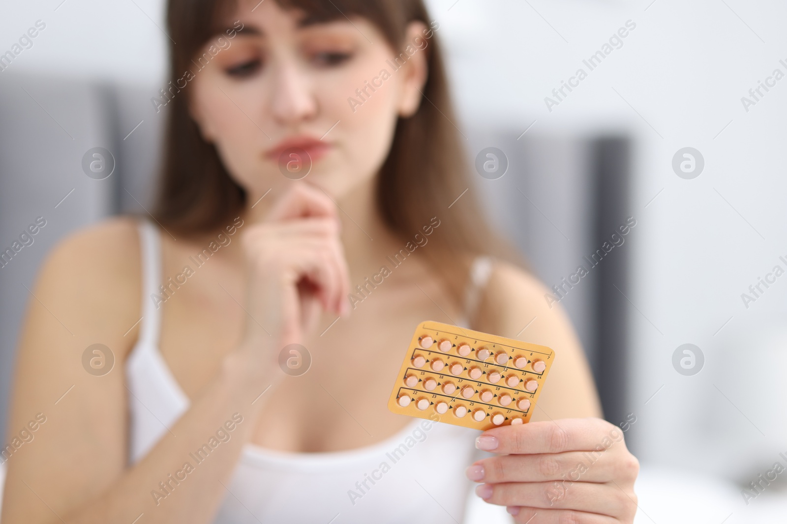 Photo of Woman with blister of contraceptive pills indoors, selective focus