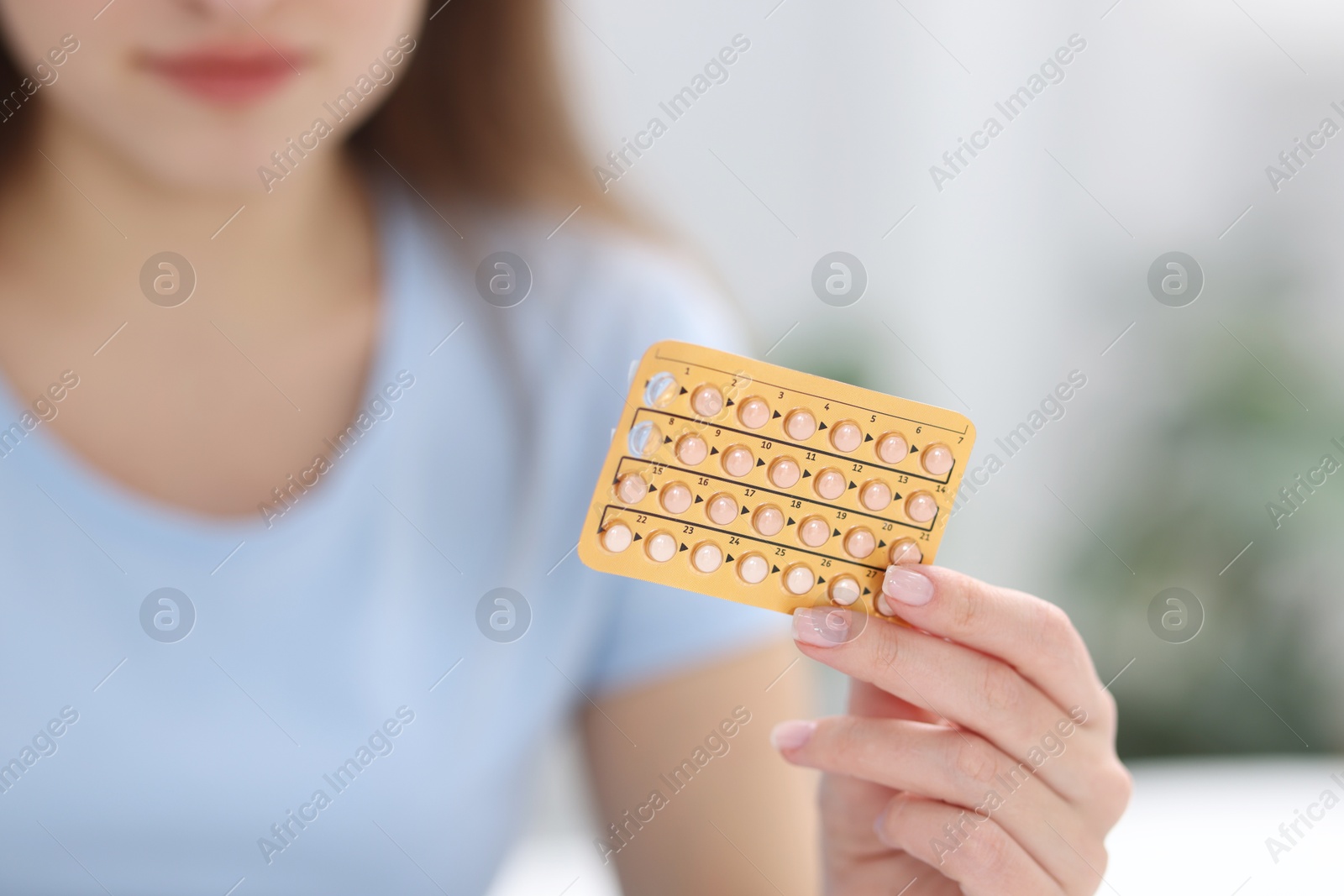 Photo of Woman with blister of contraceptive pills indoors, closeup