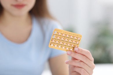 Photo of Woman with blister of contraceptive pills indoors, closeup