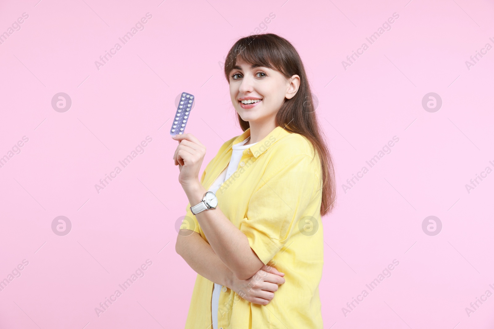 Photo of Smiling woman with blister of contraceptive pills on pink background