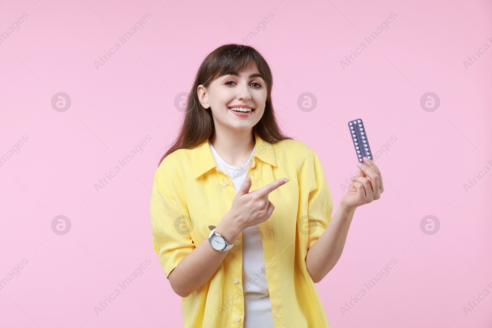 Photo of Smiling woman with blister of contraceptive pills on pink background