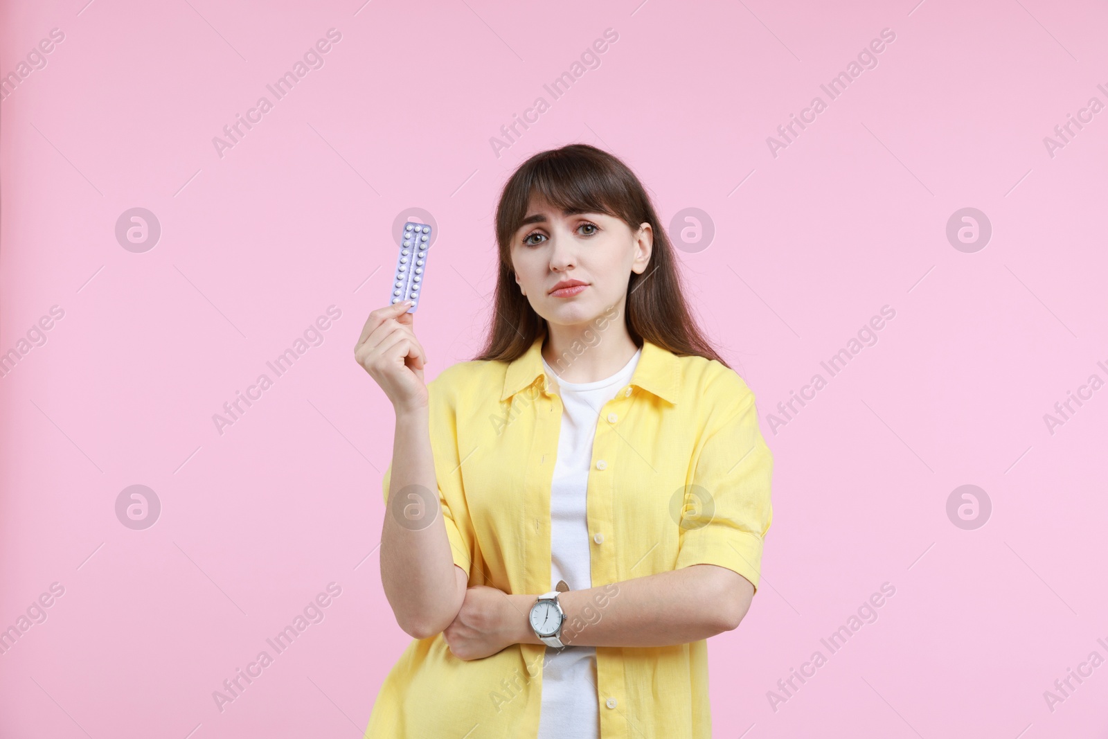 Photo of Upset woman with blister of contraceptive pills on pink background