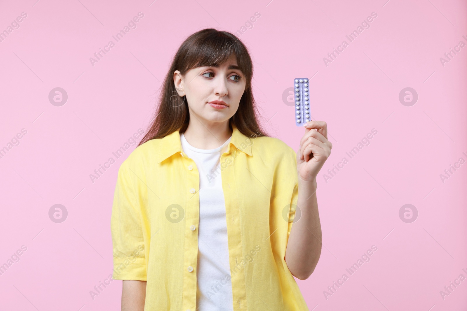 Photo of Upset woman with blister of contraceptive pills on pink background