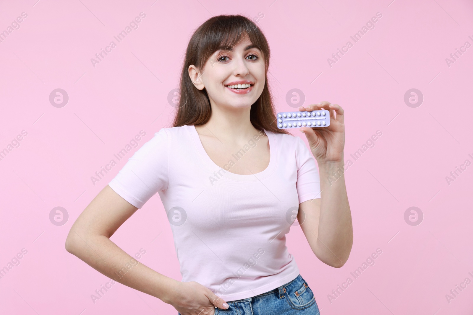 Photo of Smiling woman with blister of contraceptive pills on pink background