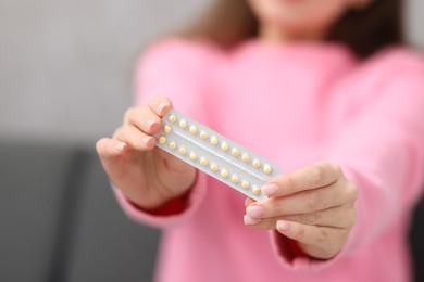 Photo of Woman with blister of contraceptive pills indoors, closeup