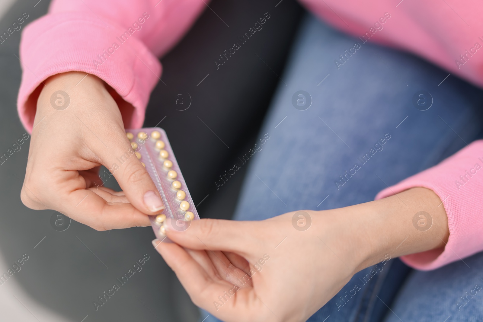 Photo of Woman taking contraceptive pill out from blister indoors, closeup