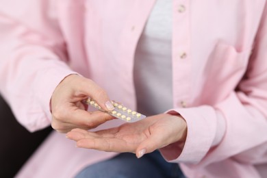 Photo of Woman taking contraceptive pill out from blister, closeup