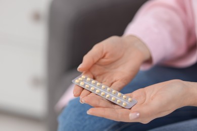 Photo of Woman with blister of contraceptive pills indoors, closeup