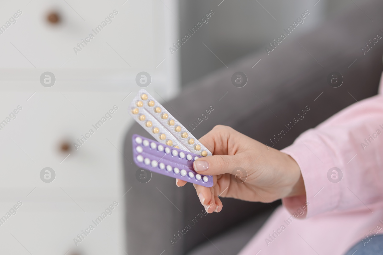 Photo of Woman with blisters of contraceptive pills indoors, closeup