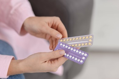 Photo of Woman with blisters of contraceptive pills indoors, closeup