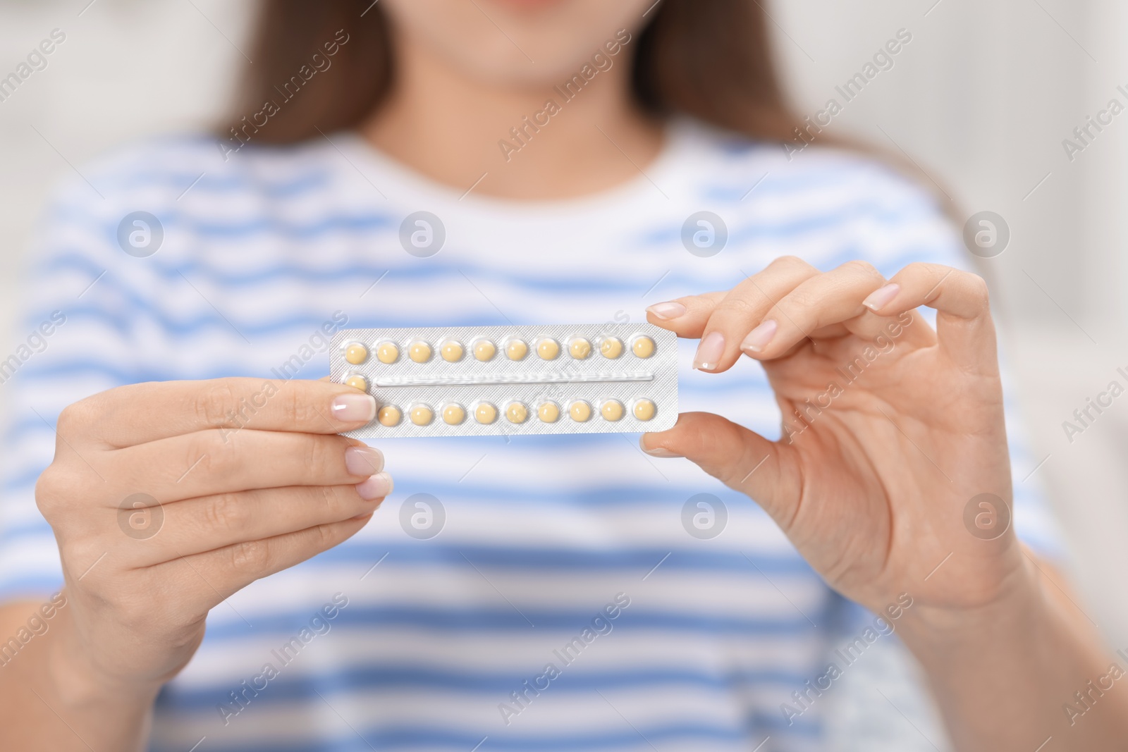 Photo of Woman with blister of contraceptive pills indoors, closeup