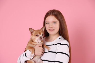 Teenage girl with her cute Chihuahua dog on pink background