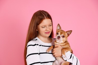 Photo of Teenage girl with her cute Chihuahua dog on pink background