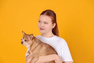 Photo of Teenage girl with her cute Chihuahua dog on yellow background