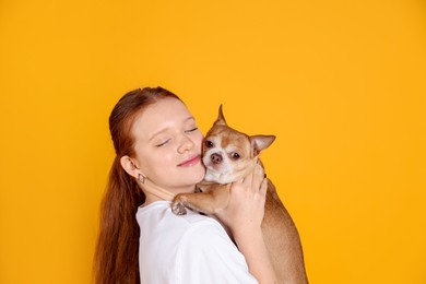 Photo of Teenage girl with her cute Chihuahua dog on yellow background, space for text