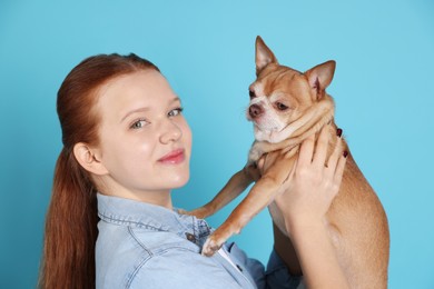 Photo of Teenage girl with her cute Chihuahua dog on light blue background