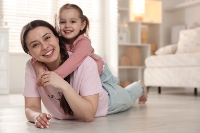 Happy mother with her little daughter spending time together at home. Space for text