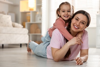 Happy mother with her little daughter spending time together at home. Space for text