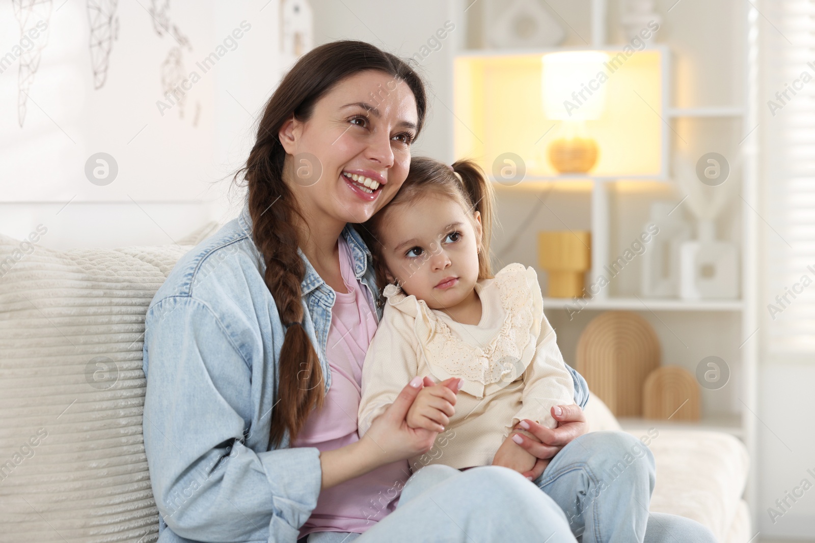 Photo of Happy mother with her cute little daughter on sofa at home