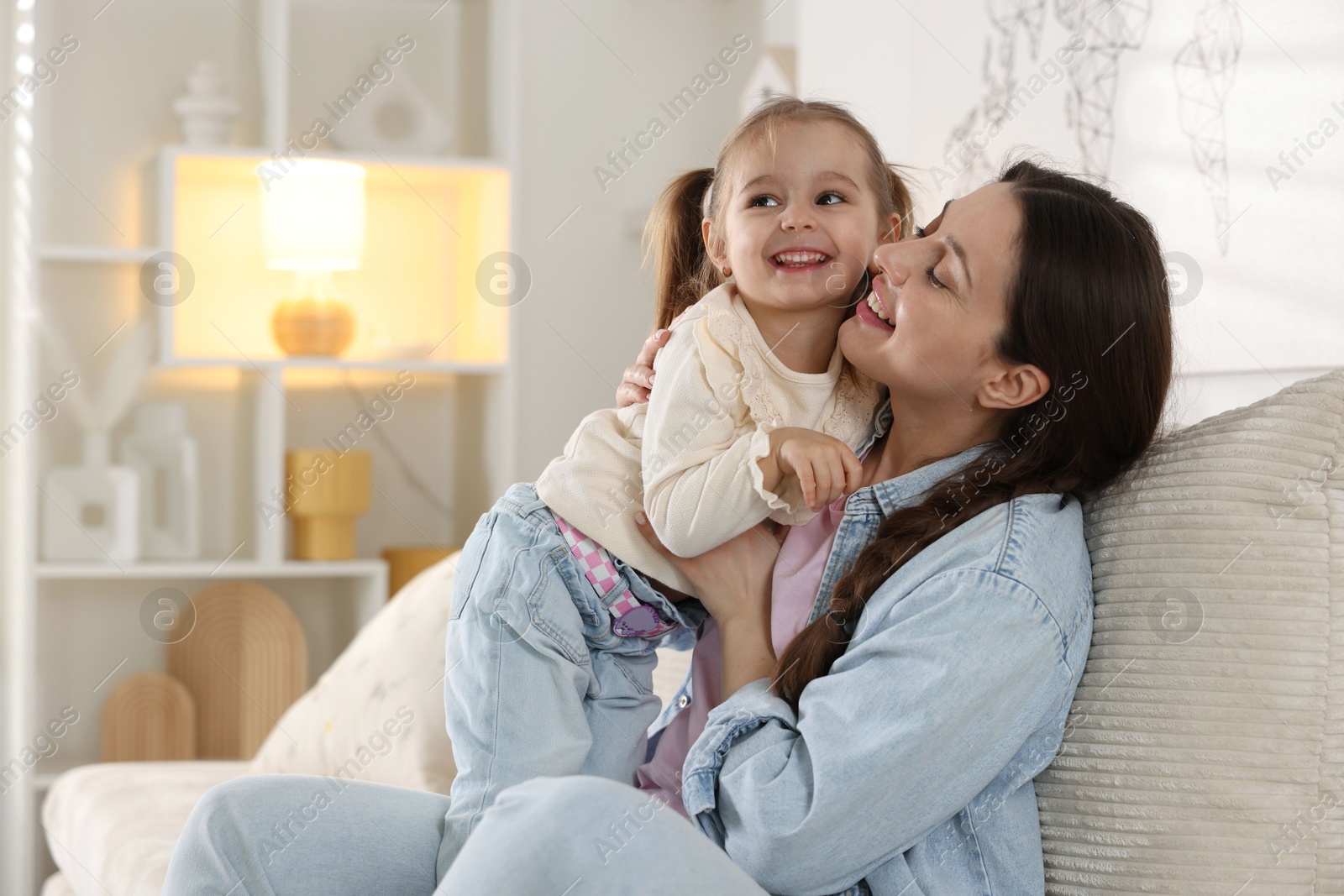 Photo of Happy mother having fun with her little daughter on sofa at home