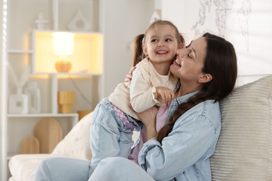 Photo of Happy mother having fun with her little daughter on sofa at home