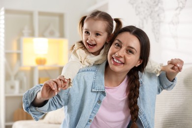 Portrait of happy mother and her cute daughter at home