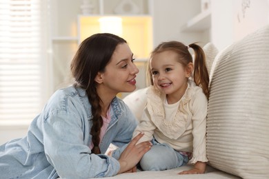 Happy mother with her cute daughter spending time together at home